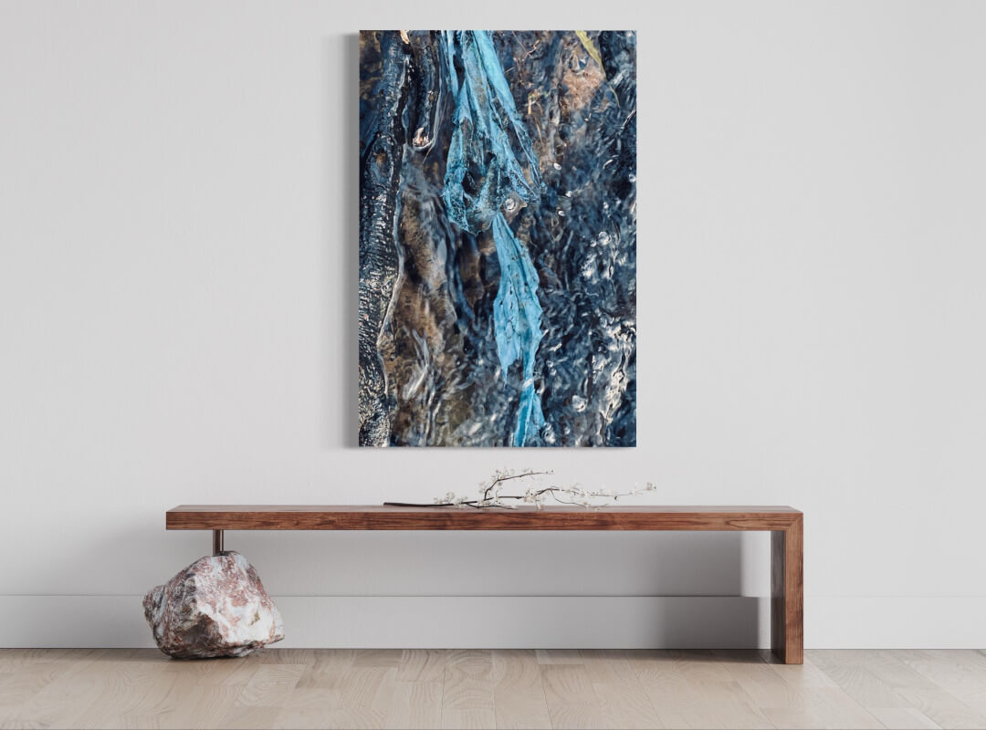 Fotografie einer in Wasser schwimmenden, blauen Folie, an heller Wand über einer hölzernen Sitzbank