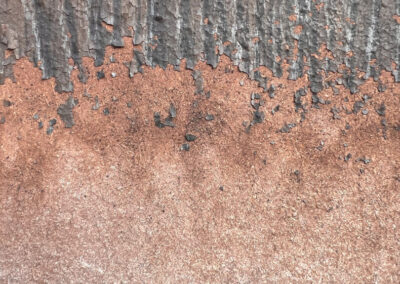 Detailfotografie eines alten Holzfensterrahmens in rötlich-bräundlich und grauen Farbtönen