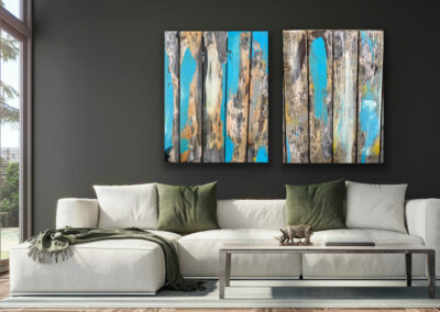 Detailfotografie der Oberfläche eines Holztisches in blau-braun-gelben Farbtönen als zwei großformatige Leinwandbilder an dunkler Wand über cremefarbener Couch.