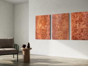 Drei Fotografien einer rostigen Oberfläche hängen an einer weißen Wand neben einer Sitzecke