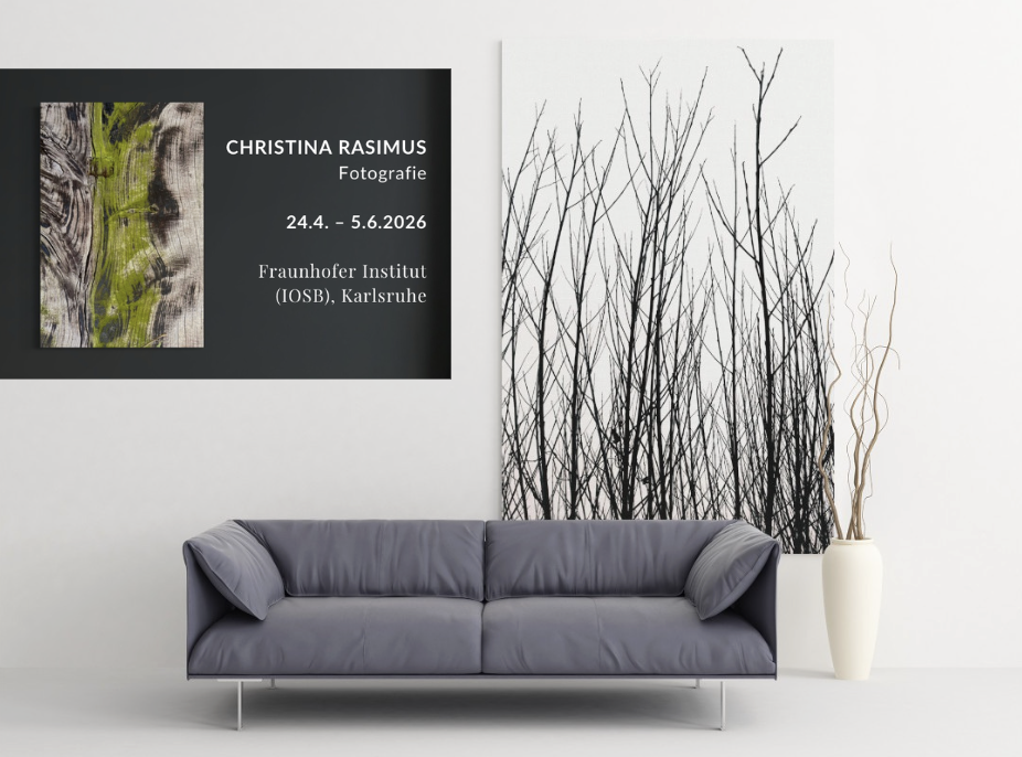 Fotografie von Weidenzweigen als Bild hinter einer grauen Couch mit Banner zur Ausstellungseinladung IOSB