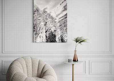 Schwarz-weiß Fotografie einer Wasserspiegelung an weißer Wand über einer Sitzecke mit beigem Sessel