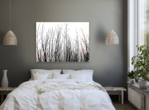Fotografie von Weidenzweigen an grauer Wand über einem weißen Doppelbett